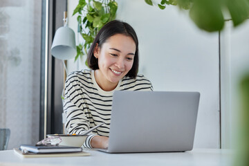 Female remore worker keyboards on laptop computer works from home on startup project smiles happily...