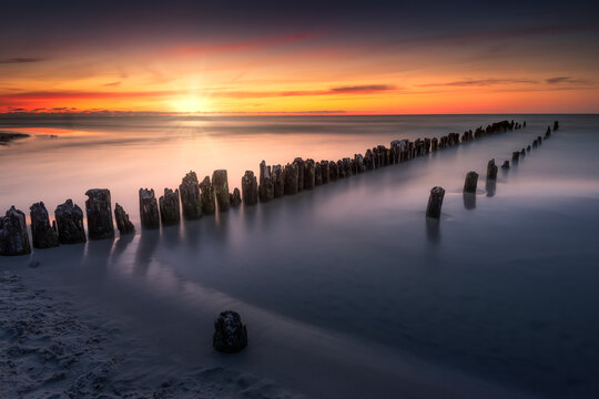 Baltic see, sunset over beach. Plaża Dębki. Wakacyjny zachód słońca nad morzem bałtyckim z widokiem na falochron i delikatne fale