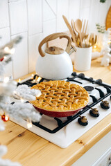 Fresh ruddy Christmas cake cools on a built-in gas hob in a Scandinavian kitchen decorated for...