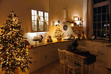 Cozy evening kitchen decorated for Christmas. Christmas tree with lots of garland lights in scandinavian kitchen with dining table. Christmas interior. Christmas Eve. Christmas dinner atmosphere.