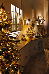 Cozy evening kitchen decorated for Christmas. Christmas tree with lots of garland lights in interior of scandinavian kitchen. New Year interior. Christmas Eve.