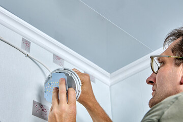An electrician mounts LED lighting on wall in residential area.
