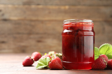 Delicious pickled strawberry jam and fresh berries on wooden table. Space for text