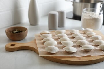 Fresh uncooked dumplings and flour on white table
