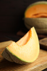 Slice of tasty fresh melon on wooden board, closeup