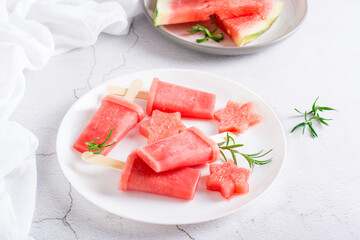 Watermelon ice cream on a stick and pieces of watermelon on a plate on the table. Homemade dessert