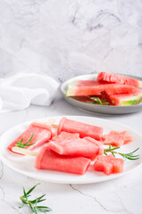 Watermelon popsicle and pieces of watermelon on a plate on the table. Homemade dessert. Vertical view