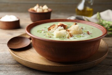 Delicious asparagus soup with croutons served on wooden table, closeup