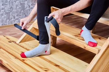 Man attached ankle foot orthosis brace on leg with velcro straps.