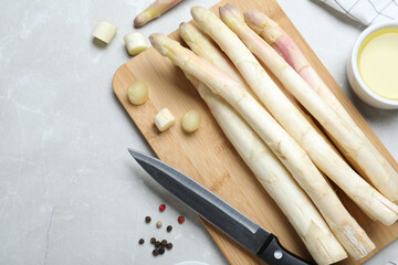 Fresh white asparagus, knife and cutting board on grey marble table, flat lay