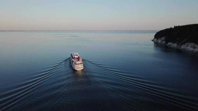 The motor ship floats on the river in Tatarstan. Big boat in the Kama river. Nature of Russia and ecology. Tourism and travel in Russia. Sunny weather at sunset and blue water. Drone footage shot 