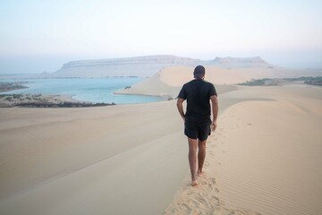 A male walking on the top of a sand hill in Fayoum - Egypt.