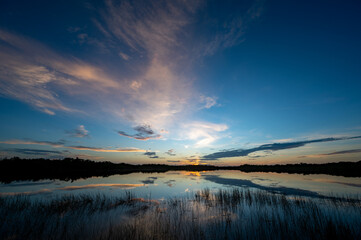 Obraz premium Colorful summer sunrise cloudscape over Nine Mile Pond reflected in perfectly calm water in Everglades National Park, Florida.