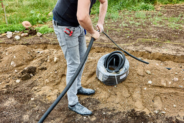 Outdoor cable work, cableman lays power cable in trench.