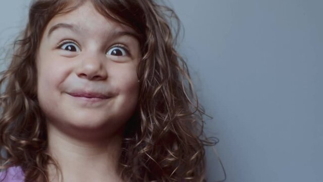 Portrait of a cute toddler girl making funny faces. 4K footage.