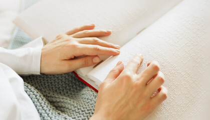 Poorly seeing woman learning Braille book. A person with blindness touches and reads with his...