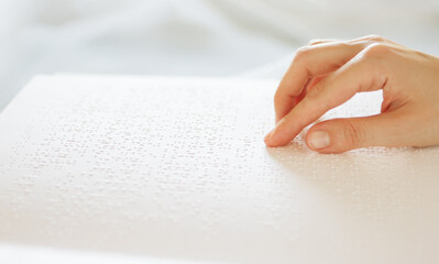 Poorly seeing woman learning Braille book. A person with blindness touches and reads with his...