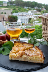 Apple products of Normandy, homemade baked apple cake, glasses of calvados and cider drink and houses of Etretat village on background, Normandy, France