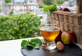Glass of cold apple cider drink and houses of Etretat village on background, Normandy, France