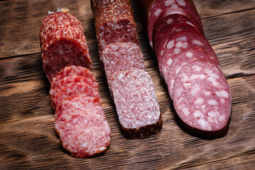 Various kinds of raw smoked sausages on the wooden kitchen table background. Top view.