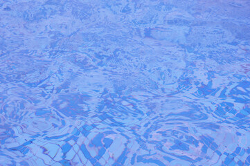 Abstract defocused background with blue pool water. Water with reflection of the sun in a pool with a mosaic bottom. View from above