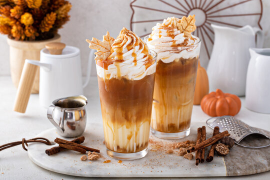 Iced pumpkin spice latte in tall glasses topped with whipped cream