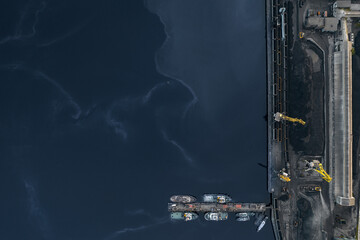 Loading coal mining in port on industry cargo ship with crane. Aerial top view