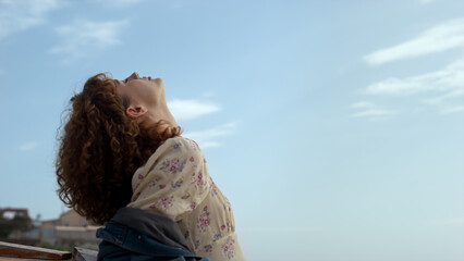 Fototapeta premium Serene girl standing beach raising face to sunlight closeup. Lady enjoy seascape