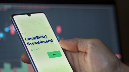 An investor's analyzing the long/short broad-based etf fund on screen. A phone shows the ETF's prices long short broad based to invest