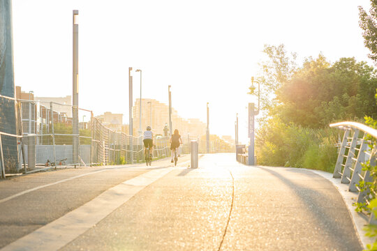 Calgary Alberta Canada, July 27 2022: Two People Riding Bikes Along A Pedestrian Pathway With Construction Fencing For Flood Mitigation Near The Downtown East Village.
