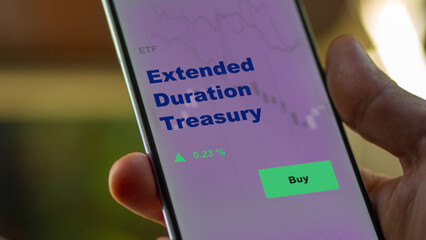 An investor's analyzing the extended duration treasury etf fund on screen. A phone shows the ETF's prices extended duration treasuries to invest