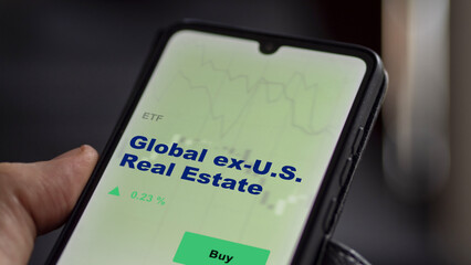 An investor's analyzing the global ex-U.S. real estate etf fund on screen. A phone shows the ETF's...