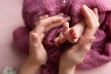 Naklejka premium the legs of the child in the arms of the mother. small feet of a newborn baby. parents hands