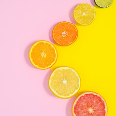 Sliced citrus fruits layout on pastel pink and yellow background. Flat lay