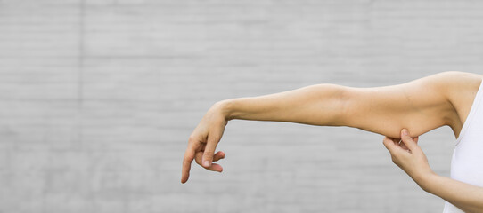 A woman shows the flabby muscles of the arm . Flabby Arm Syndrome (FAS). Effect of aging caused by loss of elasticity and muscle.Banner, copyspace. - obrazy, fototapety, plakaty
