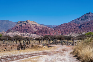 .Tranquera is the entrance door to a typical Argentine estancia in the Puna area of ​​Argentina with a woman walking from behind. The region known as Quebrada de Humahuaca