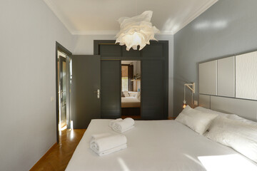 Bedroom with double bed, wardrobe with gray Venetian-style doors and another mirror, and herringbone oak flooring