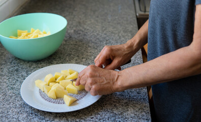 unrecognizable person preparing an omelet by cutting raw potatoes