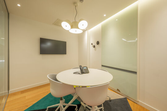 Office Cubicle With Round Table, White Swivel Chairs, Tv On The Wall And Sliding Glass Door