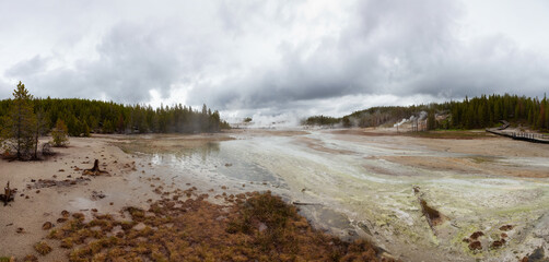 Hot spring Geyser with colorful water in American Landscape. Cloudy Sky. Yellowstone National Park, Wyoming, United States. Nature Background Panorama