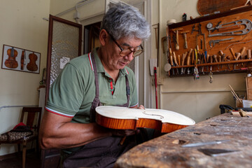 luthier carving and sculpting the f holes a violin with a knife - obrazy, fototapety, plakaty