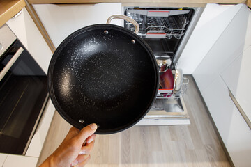 frying pan with white flakes from hard water while washing in the dishwasher in a modern smart...