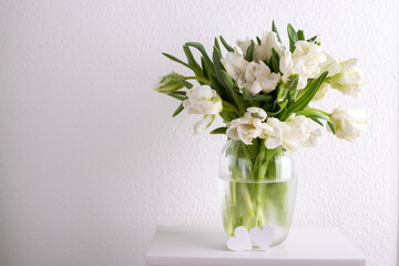 Bouquet of white tulips in a vase against white wall copy space