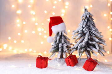 Obraz premium Christmas or new year greeting card template, red Santa's hat holiday tree on snow with bokeh lights