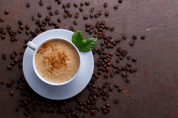 Cup of coffee cappuccino and coffee beans on the brown stone background