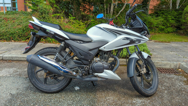 White Honda 125cc motorbike parked in a parking space