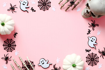 Happy Halloween holiday concept. Flat lay white pumpkins, cute Halloween decorations, spiders, web, ghosts on pastel pink background. Halloween greeting card template. Top view with copy space.