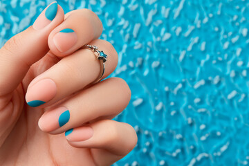 Close up womans hand with summer manicure on blue background. Manicure design trends