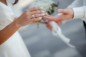 Obraz na płótnie Canvas Wedding bouquet in the hands of the bride at the ceremony. Touching the hands of the bride and groom. Wedding jewelry. Wedding rings. The tenderness and beauty of the wedding ceremony.