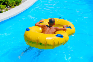 A boy swims on an inflatable ring in the pool of the water park